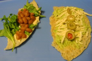 Juliet sized wraps - one half with hummus, baby arugula & homemade brown beans, the other half with guacamole, Diaya cheese & olives